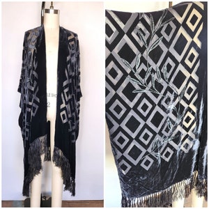 Può includere: Un kimono in velluto blu scuro con un motivo geometrico argentato e un bordo a frangia. Il motivo presenta quadrati e un disegno di foglie.