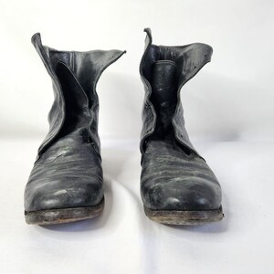 May include: A pair of black leather ankle boots with a pointed toe and a zipper on the side. The boots are worn and have a distressed look.