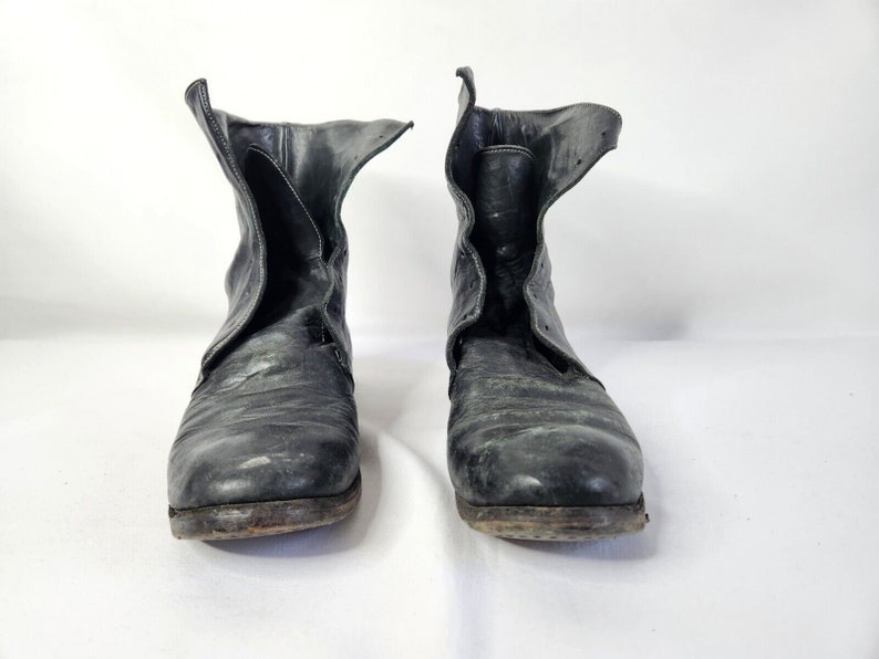 May include: A pair of black leather ankle boots with a pointed toe and a zipper on the side. The boots are worn and have a distressed look.