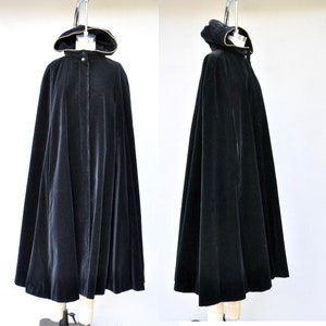 May include: A black velvet hooded cape with a gold trim. The cape has a long, flowing design and a zipper closure.