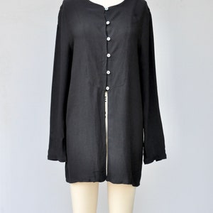 May include: A black long-sleeved shirt with a button-up front and a long slit in the back.