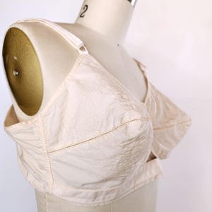 May include: A white cotton bra with adjustable straps and a hook and eye fastening. The bra has a smooth, seamless design and is made from a soft, breathable fabric.