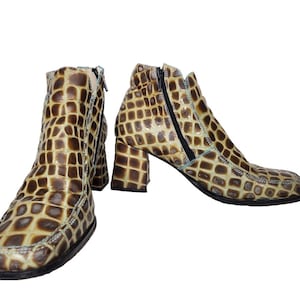 Puede incluir: Botines con estampado de reptil en tonos marrón y beige. Cuentan con punta cuadrada, tacón ancho y cremallera lateral. Un diseño único y elegante para un look moderno y a la moda.