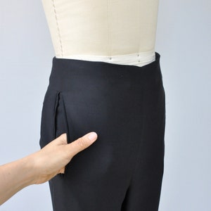 May include: Black pants with a single front pocket on a white dress form.