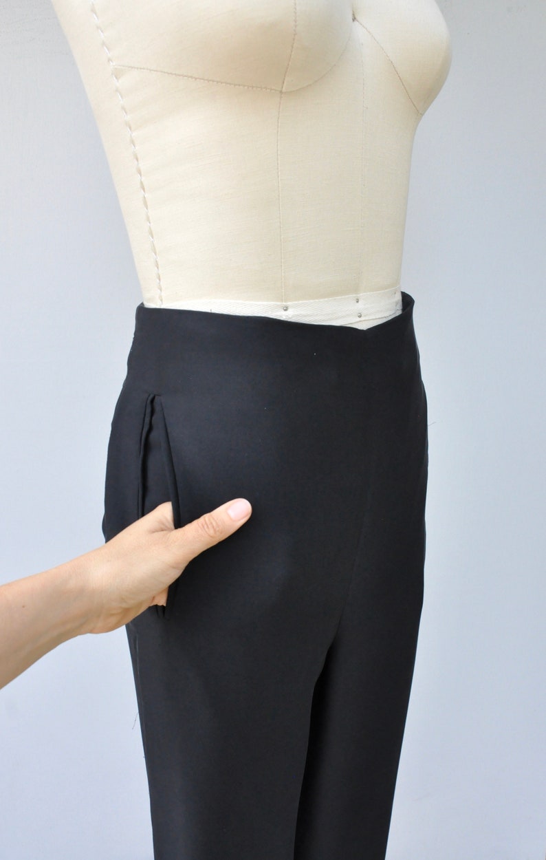May include: Black pants with a single front pocket on a white dress form.