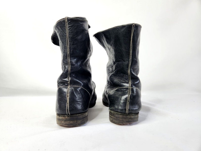 May include: A pair of black leather boots with a pointed toe and a zipper on the side. The boots have a stitched seam down the back of the shaft.