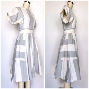 May include: A white and gray striped dress with a short sleeve and a fitted bodice. The dress has a full skirt and a patch pocket on the left side.