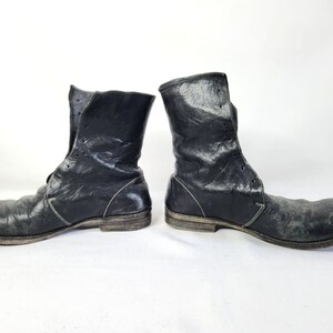 May include: A pair of black leather boots with laces and a distressed look. The boots have a rounded toe and a low heel.