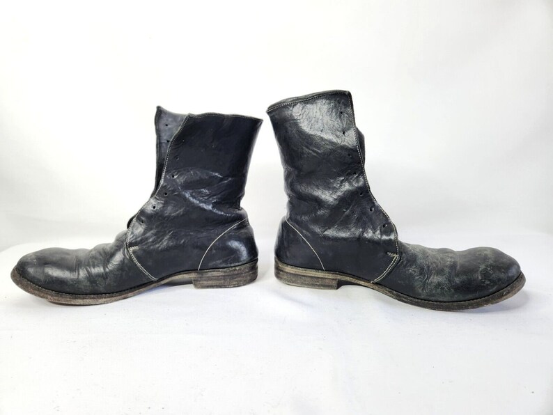 May include: A pair of black leather boots with laces and a distressed look. The boots have a rounded toe and a low heel.