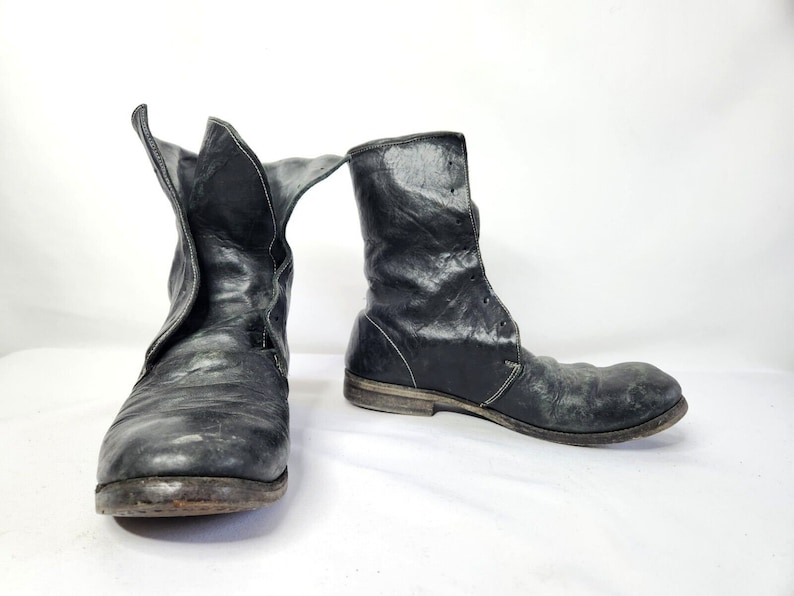 May include: A pair of black leather ankle boots with laces. The boots have a worn look and are made of a distressed leather.