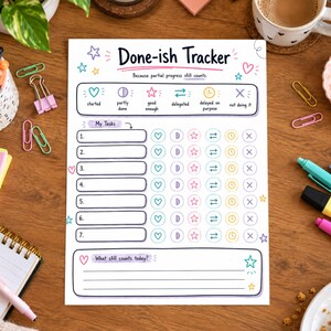 May include: A white paper task tracker titled Done-ish Tracker with the subtitle Because partial progress still counts. It features seven numbered rows with icons for status tracking including hearts, half-moons, stars, arrows, clocks, and X marks.