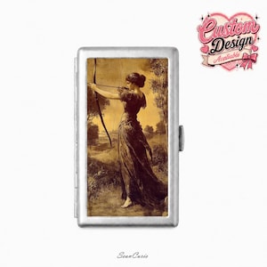 May include: A rectangular silver-toned metal case featuring a sepia-toned illustration of a figure in a long dress holding a bow and arrow in a landscape. The top right corner displays a pink heart-shaped graphic with the text Custom Design Avaliable.
