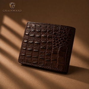 Pode incluir: Uma carteira bifold castanho-escura com um padrão de textura de pele de crocodilo. O logótipo Grainward encontra-se no canto superior esquerdo, composto por um emblema de escudo com as letras GW e o nome da marca em dourado.