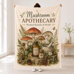 Może przedstawiać: Kremowy koc z nadrukiem tekstu Mushroom APOTHECARY Woodland Remedies & Wonder. Wzór przedstawia różne grzyby, butelki apteczne z etykietą Forest Elixir, moździerz z tłuczkiem, paprocie oraz owoce leśne.
