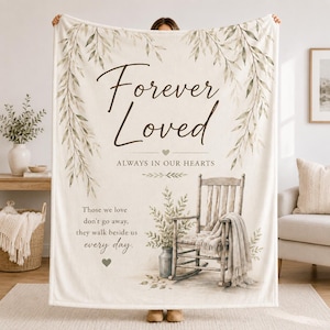 May include: A cream-colored throw blanket featuring a printed design of hanging green leaves, a wooden rocking chair with a draped cloth, and the text Forever Loved, ALWAYS IN OUR HEARTS, and Those we love don't go away, they walk beside us every day.