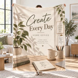 Puede incluir: Una manta de color crema con un diseño impreso de un escritorio con una planta en maceta, libros apilados, una taza con la frase 'YOU GOT THIS', un cuaderno de espiral con 'Better Ideas Ahead' y arte de pared con 'Create Every Day'.