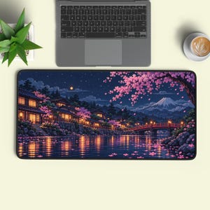 May include: A rectangular desk mat featuring a night scene of a Japanese village by a river with cherry blossom trees, a red bridge, and a mountain in the background. The illustration includes glowing lanterns, a starry sky, and pink petals.