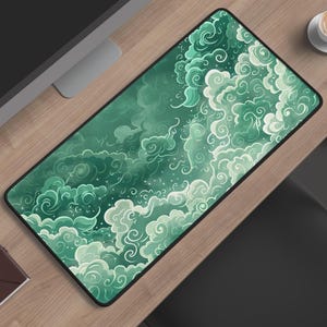 Puede incluir: Una alfombrilla de escritorio rectangular con una ilustración detallada de nubes arremolinadas en varios tonos de verde, desde tonos bosque profundos hasta reflejos de menta pálida, con un borde negro y una superficie lisa y plana.