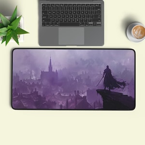 Könnte beinhalten: Eine rechteckige Schreibtischunterlage mit einer violetten Illustration einer umhangtragenden Figur mit Schwert, die auf einer Klippe steht und auf eine neblige, weitläufige Stadt mit einem markanten Kathedralenturm blickt.