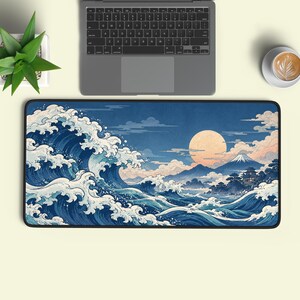 May include: A rectangular desk mat featuring a detailed illustration of a large, crashing ocean wave in shades of blue and white, with a distant mountain, a full moon, and traditional architecture set against a twilight sky background.