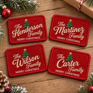 May include: Four rectangular red embroidered patches with stitched borders. Each features a green Christmas tree with a yellow star, the text "The [Name] Family" in cream script, and "MERRY CHRISTMAS" in cream block letters.