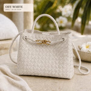 K&ouml;nnte beinhalten: Eine cremewei&szlig;e Handtasche mit geflochtener Textur, einem einzelnen Tragegriff und einem geflochtenen Schulterriemen. Die Vorderseite ist mit einem goldfarbenen Metallknoten verziert. Die Tasche misst 25 x 20 x 10 cm, wie im Bildtext angegeben.