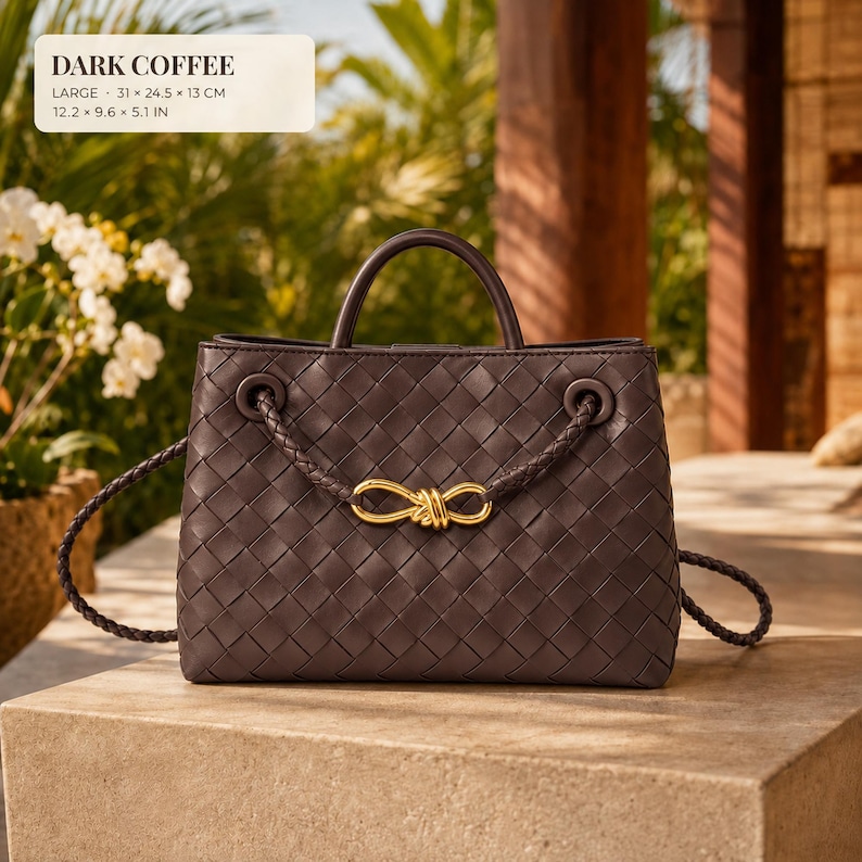 K&ouml;nnte beinhalten: Eine dunkelkaffeefarbene Handtasche mit geflochtenem Ledermuster, goldenem Schleifenakzent, geflochtenen Griffen und einem Schulterriemen. Die Tasche misst 31 x 24,5 x 13 cm, wie auf dem Textetikett angegeben.