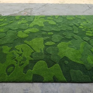 May include: A rectangular area rug featuring a textured, high-low pile surface with an abstract, organic camouflage-inspired pattern in varying shades of vibrant lime green, forest green, and deep emerald green throughout the entire design.