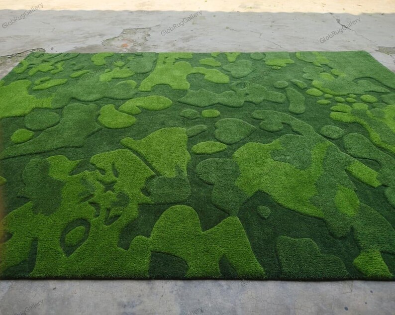 May include: A rectangular area rug featuring a textured, high-low pile surface with an abstract, organic camouflage-inspired pattern in varying shades of vibrant lime green, forest green, and deep emerald green throughout the entire design.