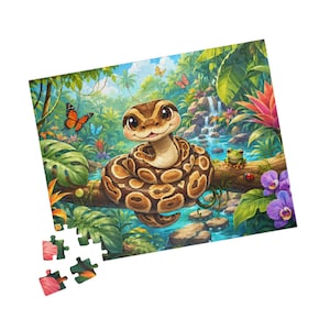 Op de afbeelding: Een legpuzzel met een cartoon koningspython opgerold op een tak in een weelderige jungle met een waterval, een kleine groene kikker, een lieveheersbeestje en kleurrijke vlinders. Vier losse puzzelstukjes liggen linksonder apart.