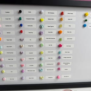 May include: A black framed white magnetic board featuring rows of small colourful beads and charms paired with white labels. The labels include text such as Coasters, Socks, Mini Notebook, Sticky Notes, Treasure Chest Item, Magnet, and Scrapbooking Journal.