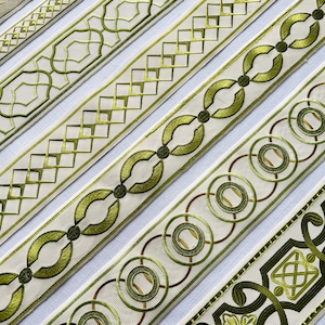 Könnte beinhalten: Eine Sammlung von fünf dekorativen Stoffbändern mit aufwendigen Stickereien in verschiedenen Grün- und Goldtönen auf cremefarbenem Hintergrund. Die Muster umfassen geometrische Gitterdesigns, ineinandergreifende Kreise und florale Motive.