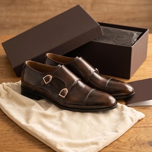 Double monk strap shoes packaged in branded dust bag, ready for gift-giving or shipping