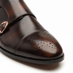 Close-up of hand-burnished patina finish on brown leather cap toe with brogue perforation