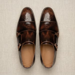 Flat lay top-down view of hand painted dark brown double monk strap shoe pair