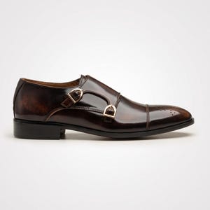 Side profile of double monk strap shoe showing gold-tone buckle closures
Detail shot of gold buckle hardware on hand painted brown leather monk strap shoe
