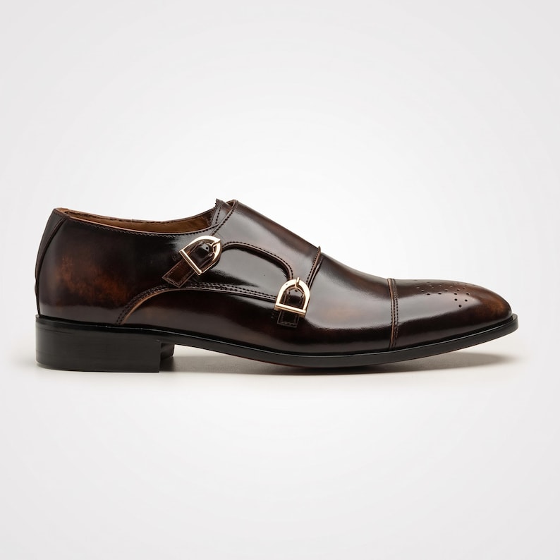 Side profile of double monk strap shoe showing gold-tone buckle closures
Detail shot of gold buckle hardware on hand painted brown leather monk strap shoe