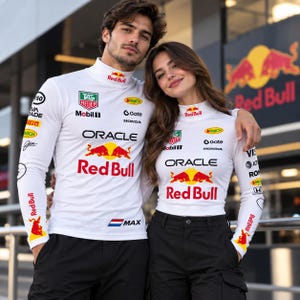 May include: Two individuals wearing white long-sleeve mock neck shirts featuring Red Bull, Oracle, TAG Heuer, Mobil 1, and Honda logos. The shirts have red and yellow bull graphics, and the left shirt includes the text MAX and a Dutch flag.