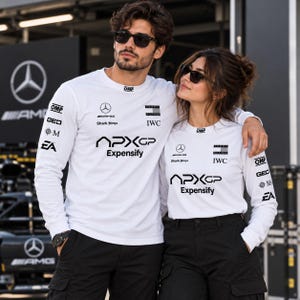 May include: Matching white long-sleeve shirts featuring black logos including APXGP, Expensify, Mercedes-AMG, Tommy Hilfiger, IWC, OMP, Shark Ninja, GEICO, and EA. The shirts have crew necks and are paired with black cargo pants.