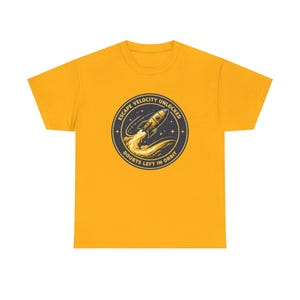 May include: A mustard yellow short-sleeve t-shirt featuring a circular graphic on the chest. The design depicts a rocket launching into space with a trail of smoke, surrounded by stars and the text ESCAPE VELOCITY UNLOCKED DOUBTS LEFT IN ORBIT.
