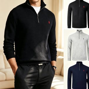 May include: A long-sleeve quarter-zip pullover sweater featuring a high collar, a silver-toned metal zipper, and a small embroidered logo on the left chest. The sweater is available in solid black, light gray, and navy blue color options.