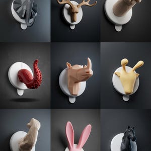 Può includere: Una collezione di nove ganci da parete con vari design ispirati agli animali, tra cui un elefante, un alce, una zampa, un tentacolo di polpo, un rinoceronte, una giraffa, un braccio, orecchie di coniglio e una testa di cavallo su basi bianche.