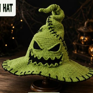 Pode incluir: Um chapéu de crochê verde-limão com topo pontiagudo e caído e aba larga. O chapéu exibe um rosto preto costurado com olhos triangulares irregulares e um sorriso largo e dentado. Pontos pretos acentuam a aba e a lateral do chapéu.