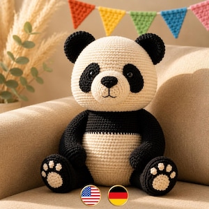 May include: A handcrafted crochet panda bear toy featuring a cream-coloured head and torso with black limbs, ears, and eye patches. The panda has black safety eyes, a stitched nose, and cream-coloured paw pads with black detailing on the feet.