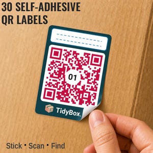 Può includere: Un'etichetta QR autoadesiva rettangolare con un bordo verde acqua scuro, una sezione superiore bianca con linee tratteggiate per scrivere e un codice QR rosso centrale con il numero 01. L'etichetta include il logo TidyBox e il testo 30 SELF-ADHESIVE QR LABELS.