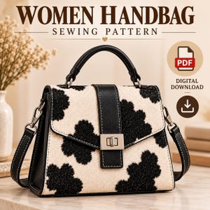 May include: A handbag sewing pattern featuring a digital download PDF icon. The handbag has a cream-colored body with a black floral-like pattern, a black top handle, a black vertical center strap, and a silver-toned metal turn-lock closure.