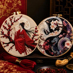 Peut inclure: Deux tambours à broder circulaires présentant des travaux d'aiguille détaillés. Le tambour de gauche représente une personne en robe rouge assise sur une branche fleurie devant une lune. Celui de droite montre un motif yin-yang avec un dragon blanc et un dragon bleu.