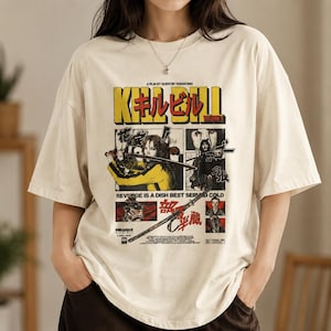 May include: An off-white short-sleeve t-shirt featuring a graphic print from the film Kill Bill Volume 1. The design includes yellow text, Japanese characters, and multiple panels depicting scenes with a sword, along with the text Revenge is a dish best served cold.