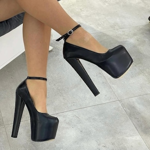 May include: A pair of black high-heeled platform pumps featuring a square toe design, a thick block heel, and a thin ankle strap with a small silver-toned metal buckle closure. The shoes have a smooth finish and a high platform sole.