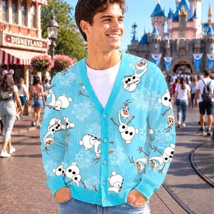 May include: A light blue V-neck cardigan featuring an all-over print of the character Olaf from Frozen, interspersed with white snowflake patterns. The garment has a button-down front closure, long sleeves, and ribbed cuffs and hem.